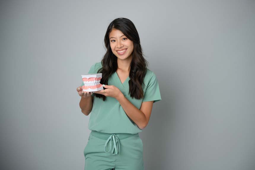 Dr. Thu Hoang holding a dental model and smiling